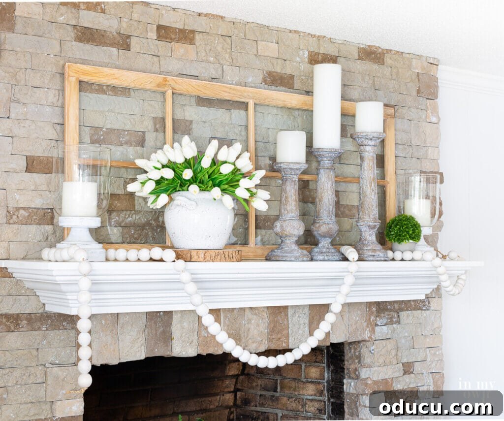 Stunning white and green summer themed mantel decor adorning a rustic stone fireplace, creating a serene and natural ambiance.