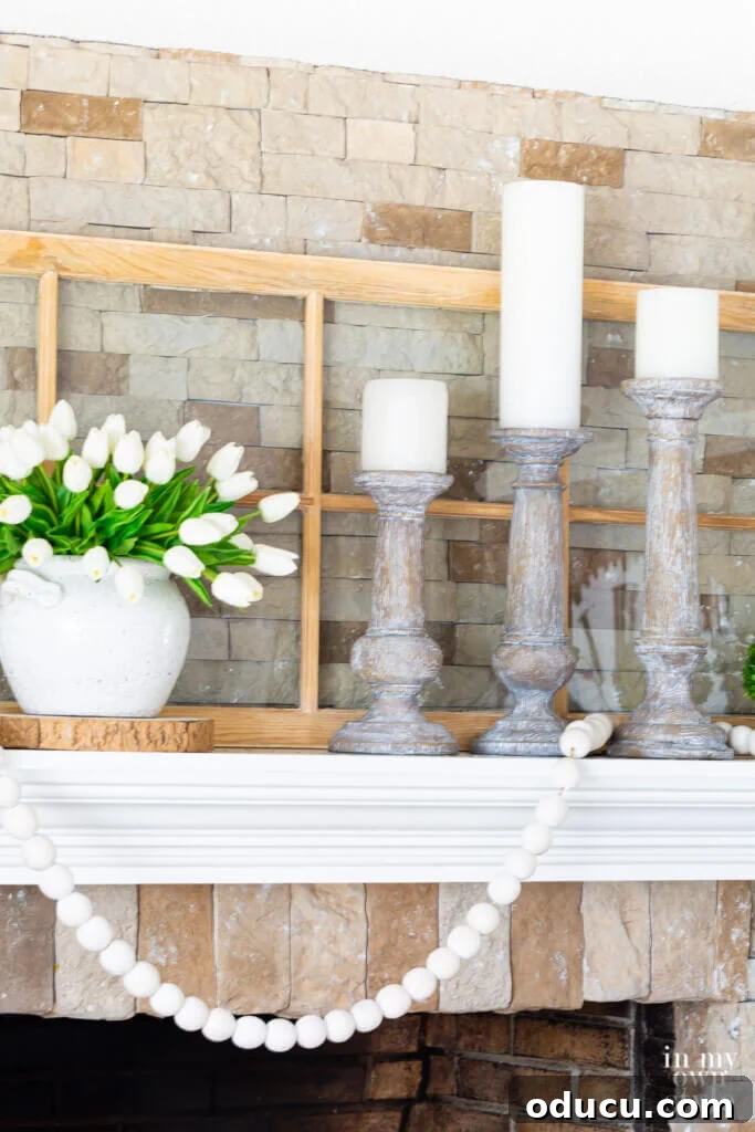 A trio of elegant white-washed wood candle holders featuring pristine white pillar candles, gracing a summer fireplace mantel.