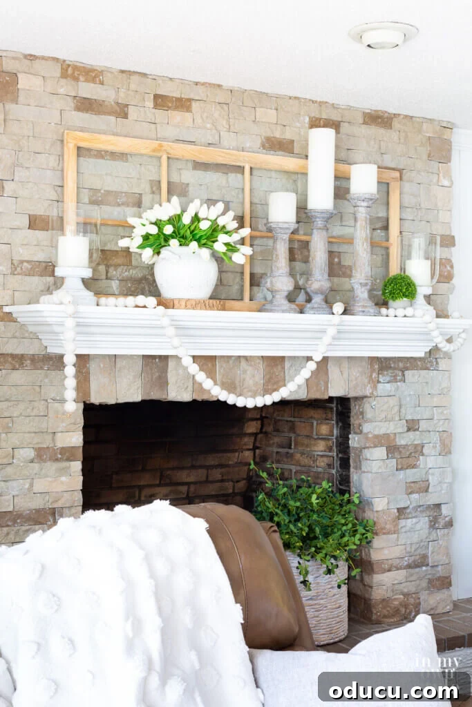 Beautiful white and green summer themed mantel decor on a rustic stone fireplace, offering elegant inspiration for seasonal home styling.
