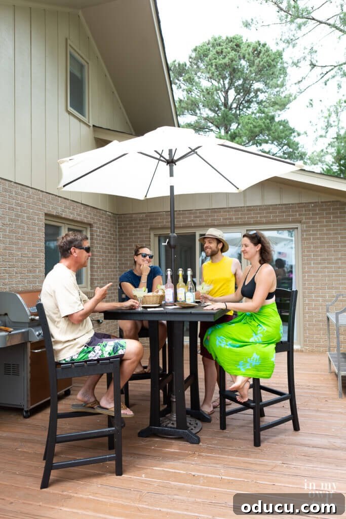 Transforming My Deck with POLYWOOD Outdoor Furniture 4 A lively scene around the POLYWOOD 5-piece La Casa Cafe Farmhouse Trestle Bar Set, with friends and family enjoying drinks and conversation outdoors.