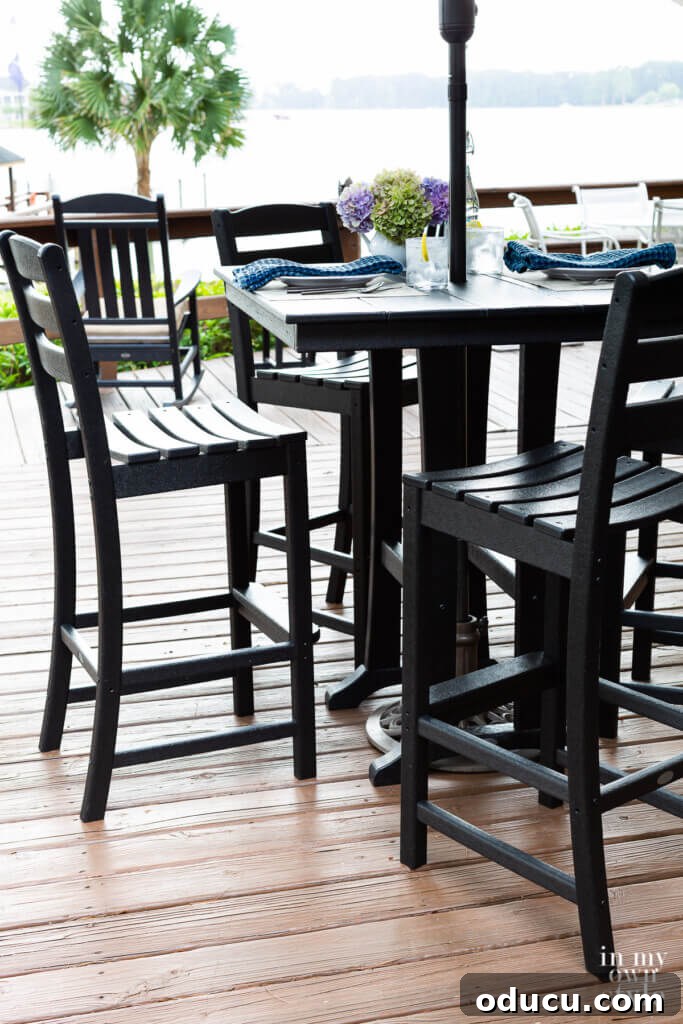 Transforming My Deck with POLYWOOD Outdoor Furniture 5 A stunning black POLYWOOD outdoor bar height dining set situated on a deck, offering an unobstructed view of the lake. It creates an ideal setting for outdoor entertaining.