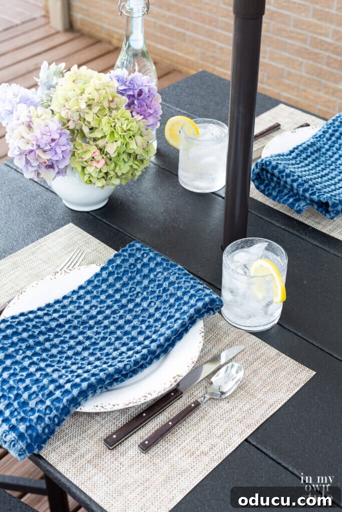 Transforming My Deck with POLYWOOD Outdoor Furniture 6 The POLYWOOD bar height table set for an elegant outdoor dining experience, complete with placemats, plates, and a floral centerpiece.