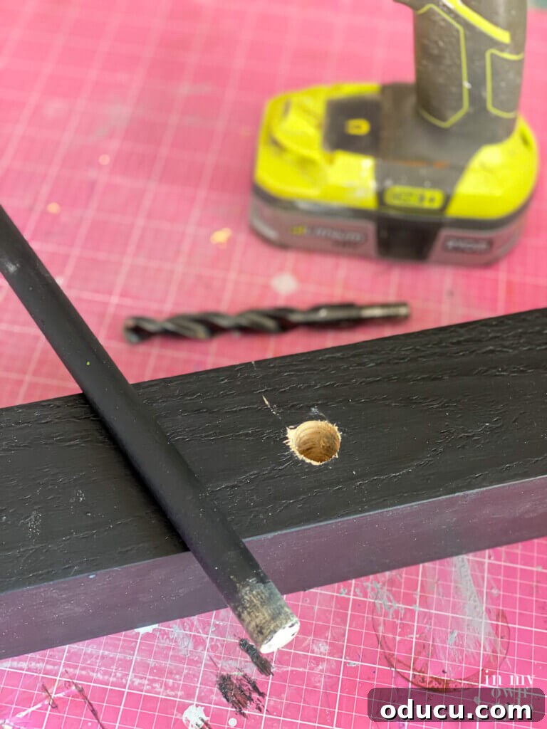 Craft a Natural Driftwood Art Display 12 Painted stand and dowels ready, with marked drill points visible on the driftwood for precise hole creation.