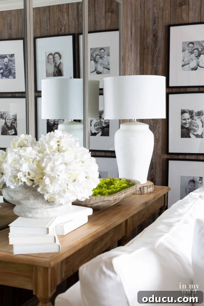Grand Living Room on a Small Budget: $240 Makeover 4 Stylish console table adorned with white and green decor, backed by a striking trio of large wall mirrors, enhancing depth and light.