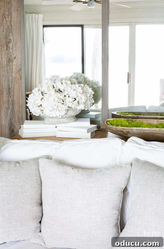 Grand Living Room on a Small Budget: $240 Makeover 7 The reflection of the opposite side of a living room captured beautifully in a large wall mirror, enhancing the room's depth.