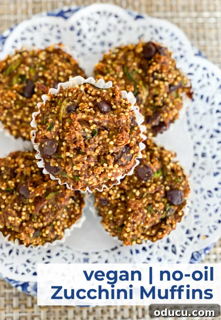 Vegan no-oil zucchini muffins stacked on a doily covered blue and white plate. This whole-food, plant-based zucchini muffin recipe has a surprise ingredient. It is what makes the muffins taste so good. Moist with a little bit of crunch.