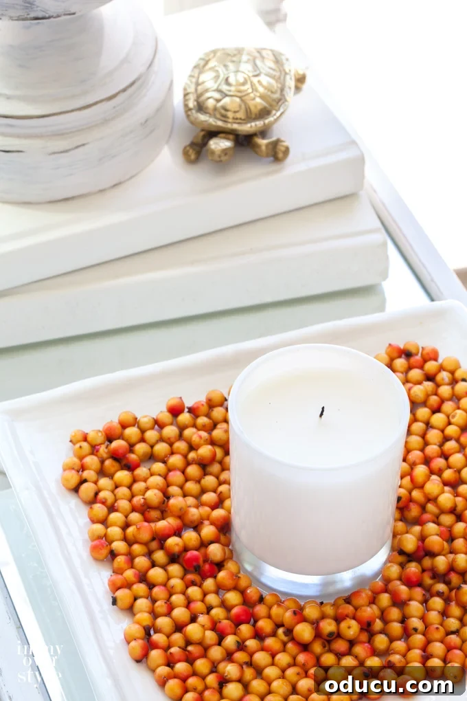 Candle on white square tray with orange beans.