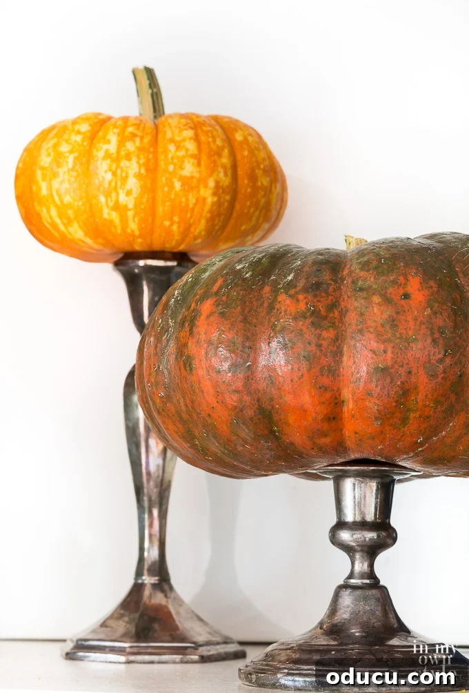Pumpkins perched on candlestick along a fireplace mantle.