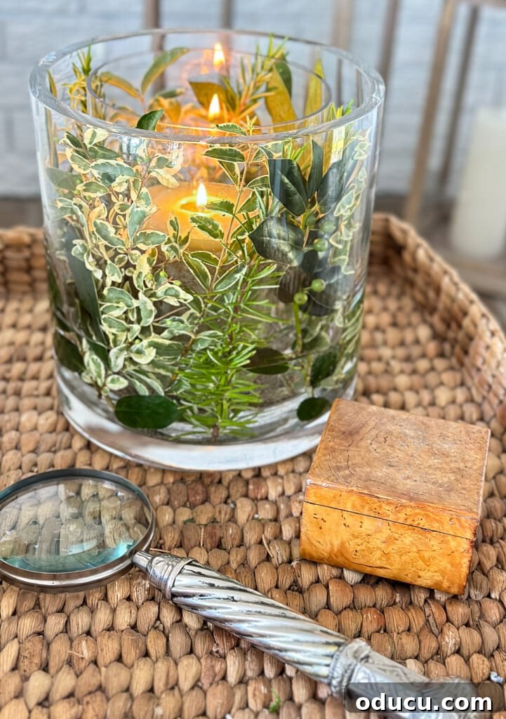 Close up of fresh herb and greenery DIY candle vase on a wicker tray table in a living room.