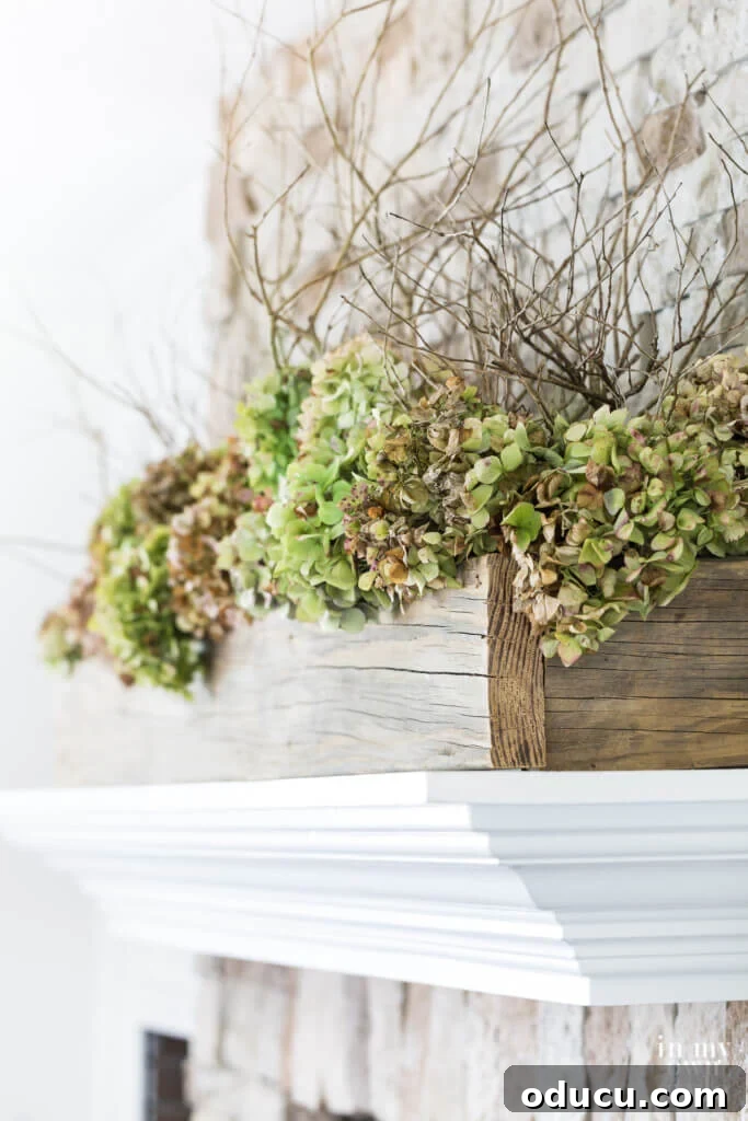 Long reclaimed wood planter with dried hydrangeas on white mantel.