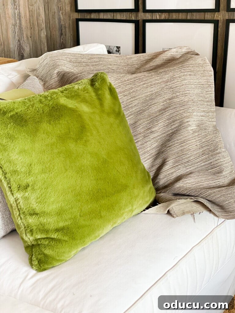 Instant Home Updates with Throw Pillow Covers 7 An olive green velvet toss pillow elegantly placed on a white sofa, with a contrasting tree bark-textured fabric nearby.