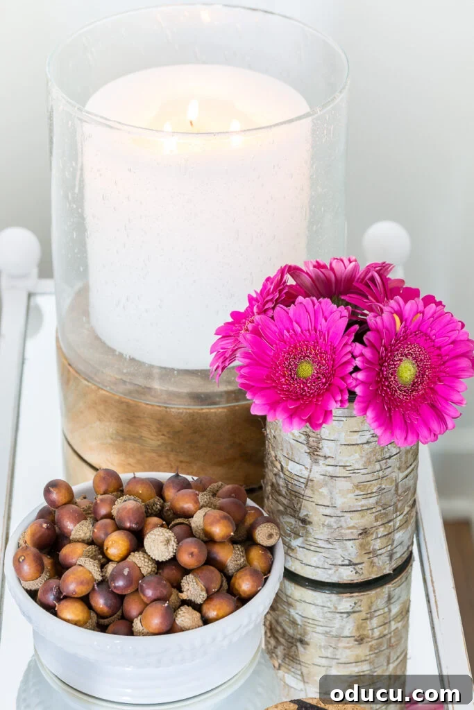 Cozy Autumn Vases: Effortless Ideas for a Warm Home 13 Pretty pink flowers on mirror table with a white candle and a bowlful of acorns.