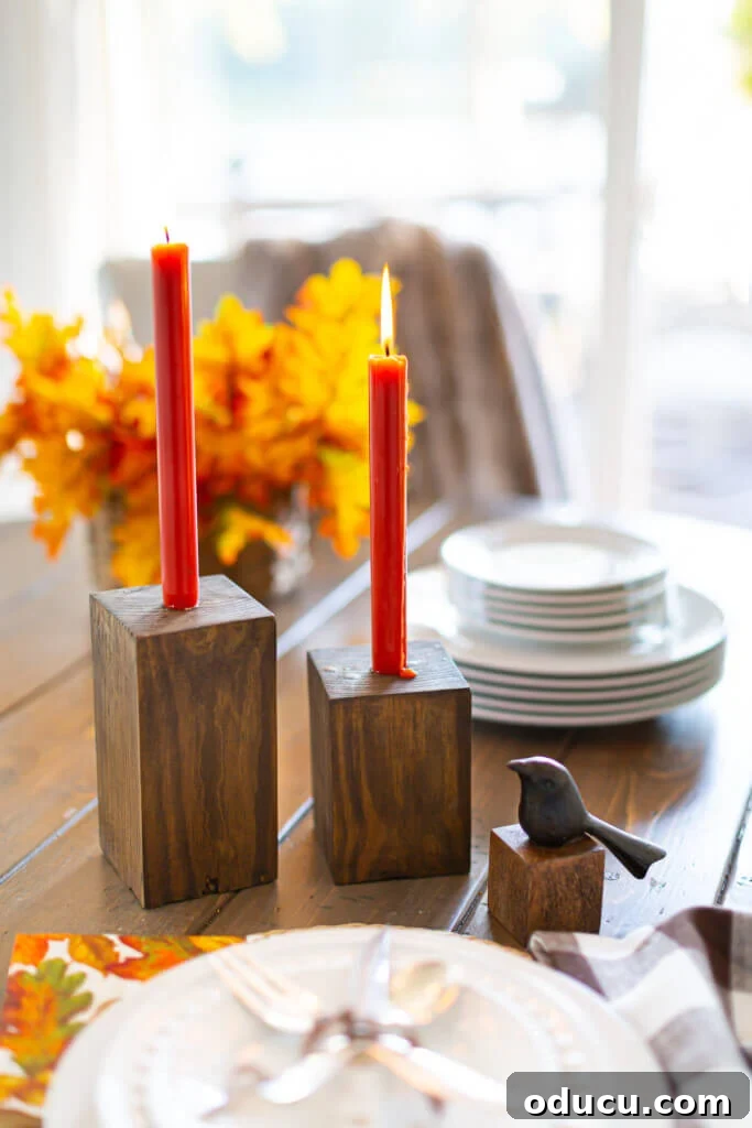 Transform Wood Scraps Into Beautiful Candle Holders Easily 2 Completed DIY Wooden Candle Holders on a dining table with dark orange taper candles.