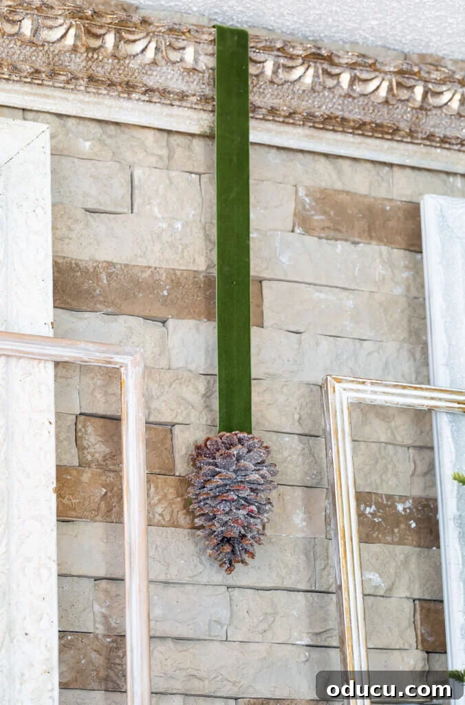 Festive Without the Fuss: Our Christmas Home Tour 2 Green velvet ribbon with glittered pinecone attached hanging from ornate gold frame, symbolizing simple, natural Christmas decor.