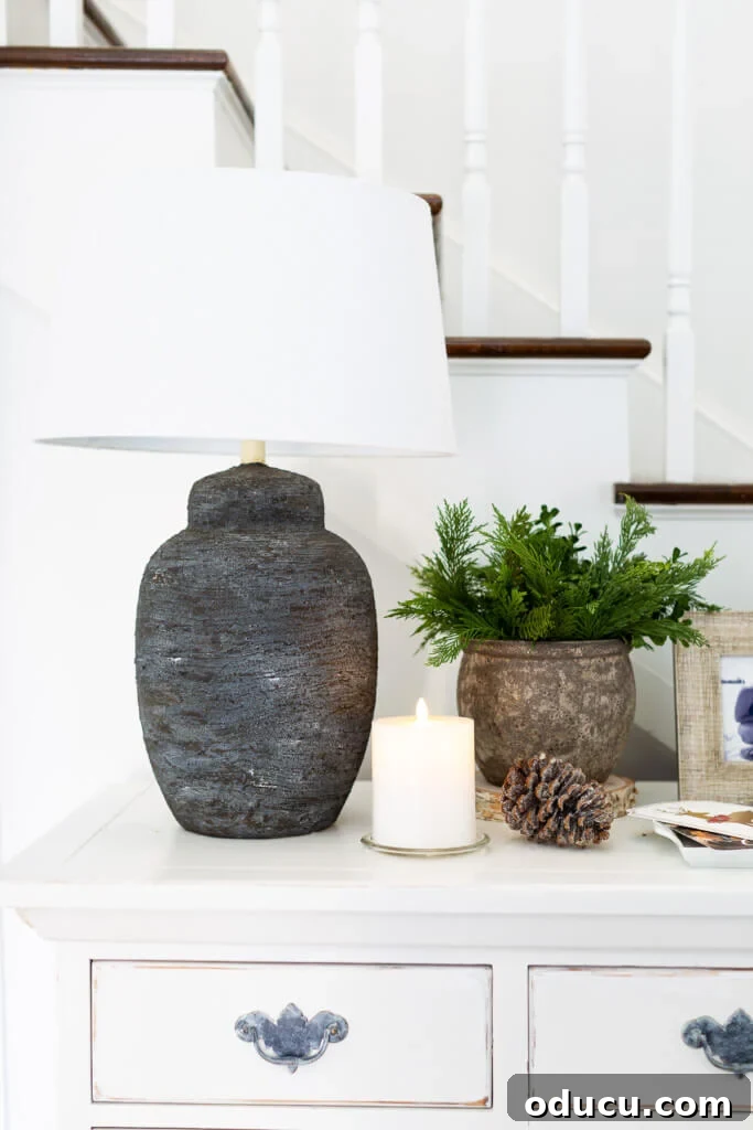 Festive Without the Fuss: Our Christmas Home Tour 13 A modern black-based lamp and natural Christmas decor elements resting on an entryway console table, exuding contemporary rustic charm.