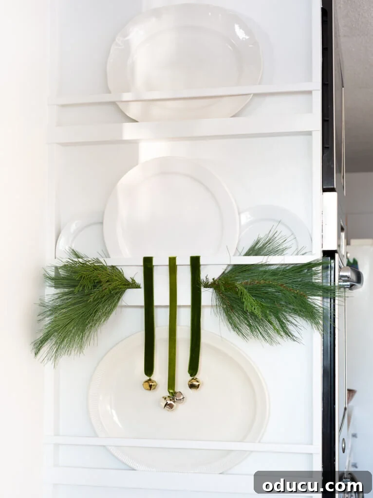 Festive Without the Fuss: Our Christmas Home Tour 18 A close-up of a plate rack wall adorned with sprigs of pine and whimsical jingle bells, highlighting the intricate details of the festive decor.