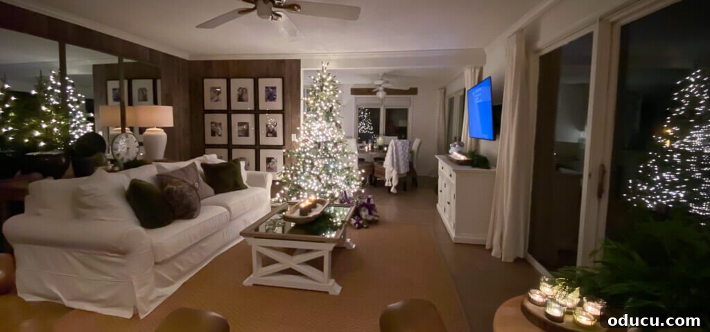 Festive Without the Fuss: Our Christmas Home Tour 25 A wide-angle, night-time shot of a living room that appears to have four twinkling Christmas trees due to enchanting reflections.