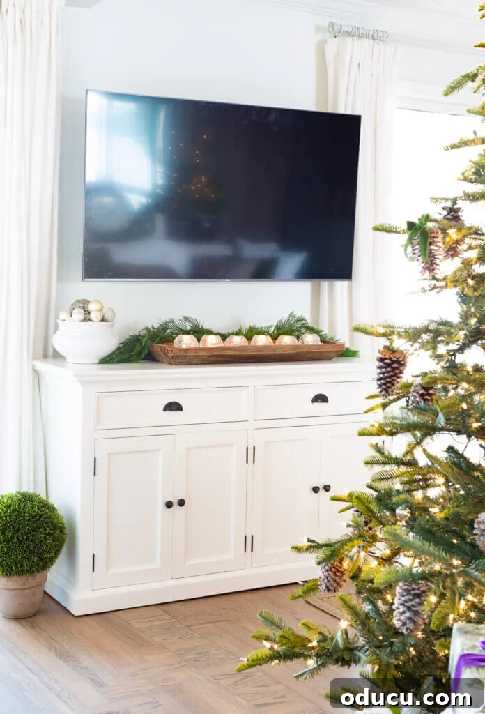 Festive Without the Fuss: Our Christmas Home Tour 8 A console cabinet beneath a television, tastefully decorated for Christmas with a focus on understated elegance.