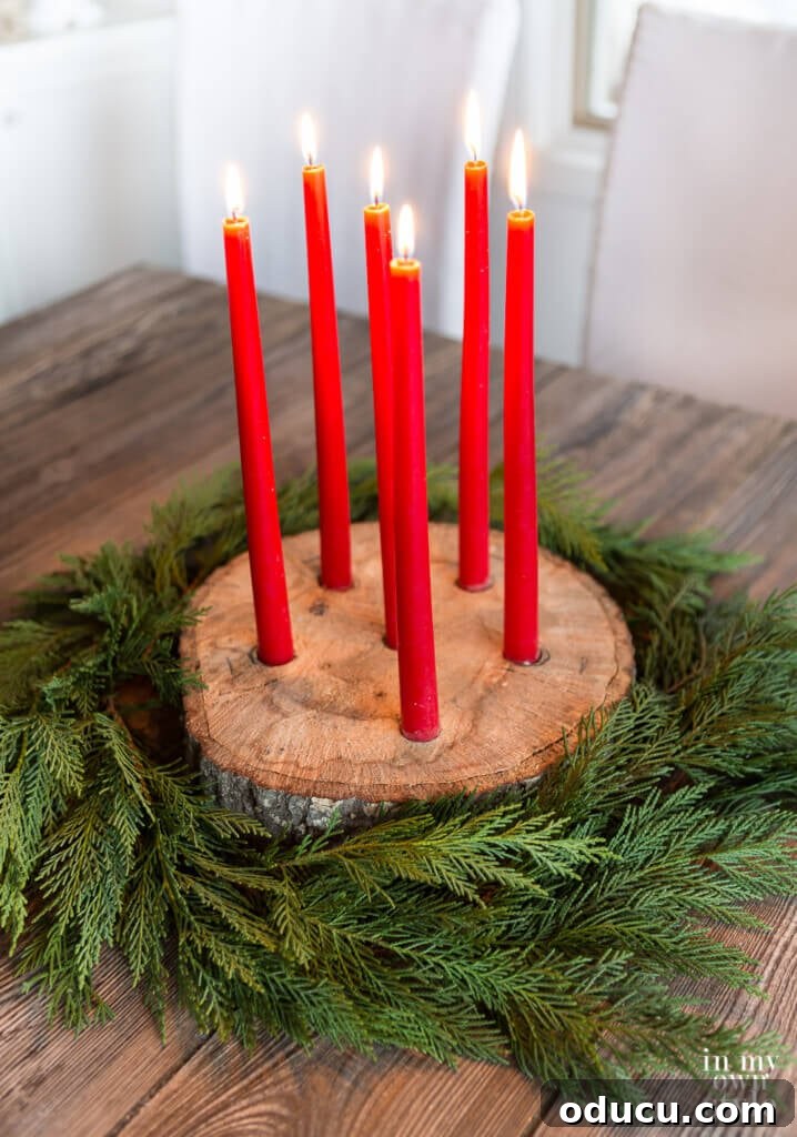 Unlock New Decor Ideas for Candle Holders 23 A festive tree trunk slice taper candle holder adorned with cedar branches for Christmas decor.