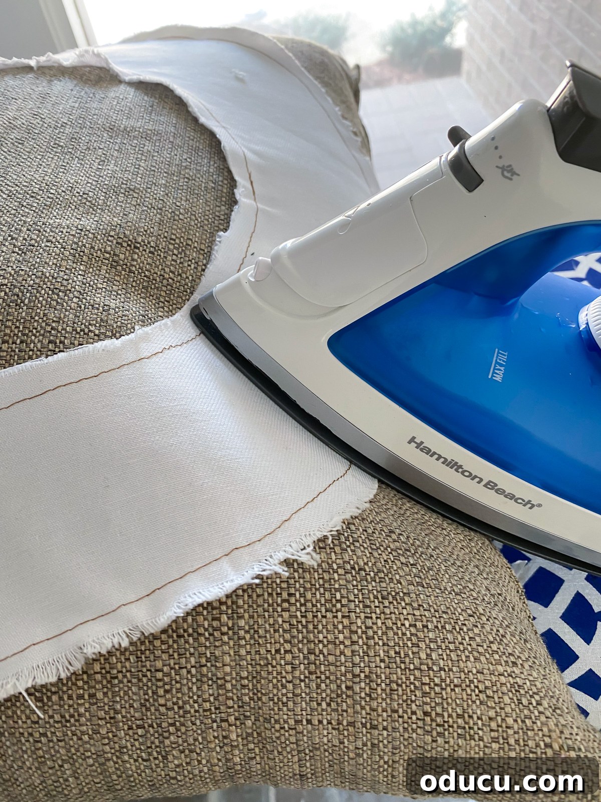 Ironing a fabric letter applique onto a pillow, securing it in place with heat for a lasting finish.