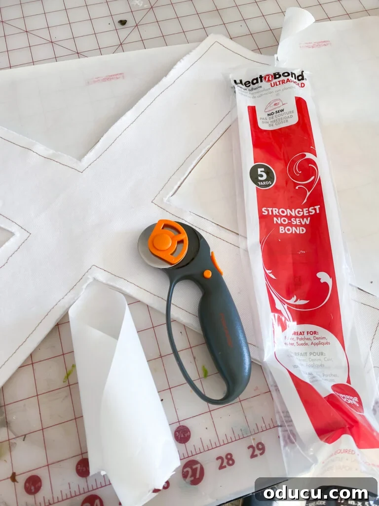 Craft Personalized XO Applique Pillows 7 Crafting essentials: a letter applique pattern, rotary cutter, and Heat n' Bond fusible web on a clean work table.