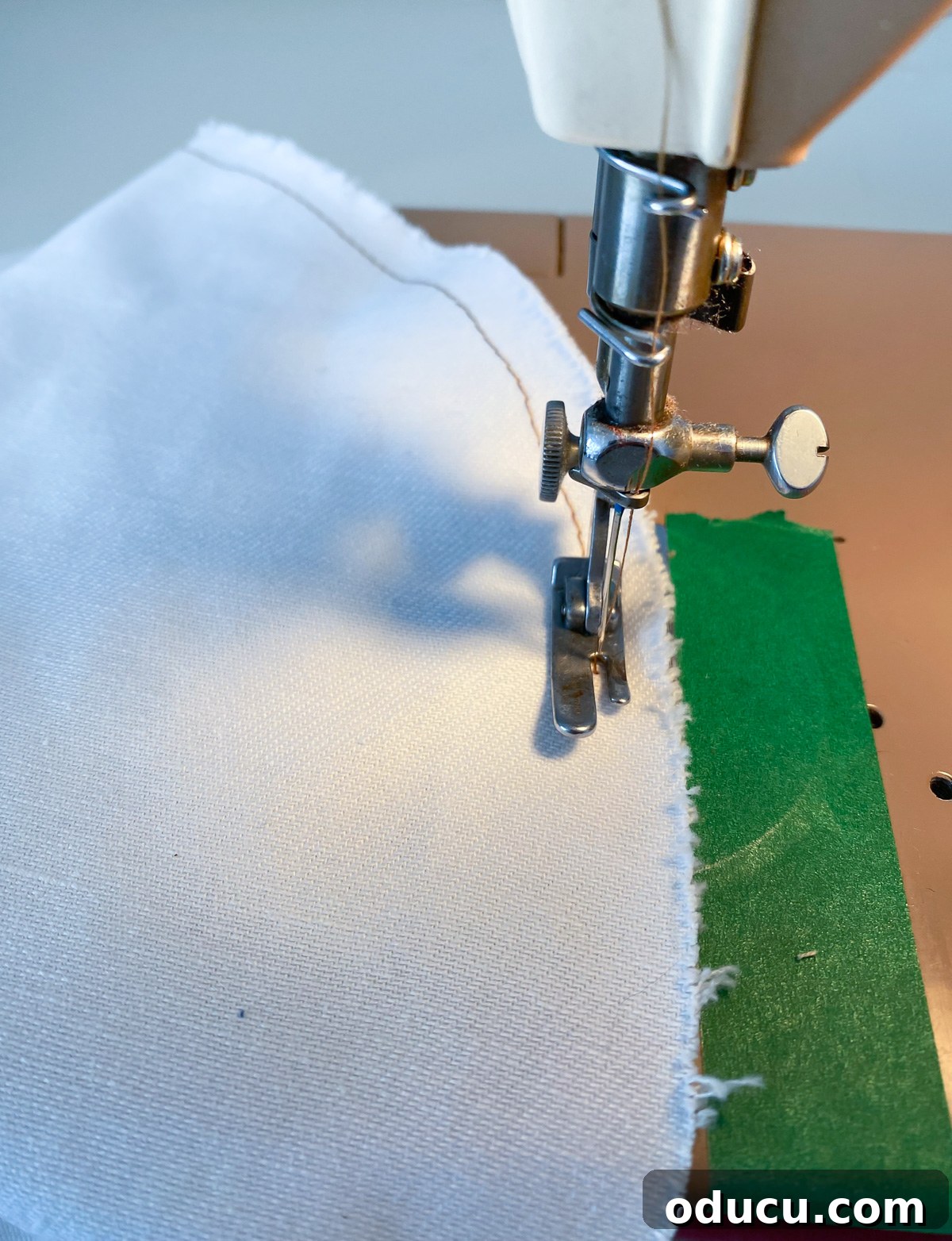 Close-up of a sewing machine adding an outline stitch to a fabric letter applique, enhancing its handmade charm.