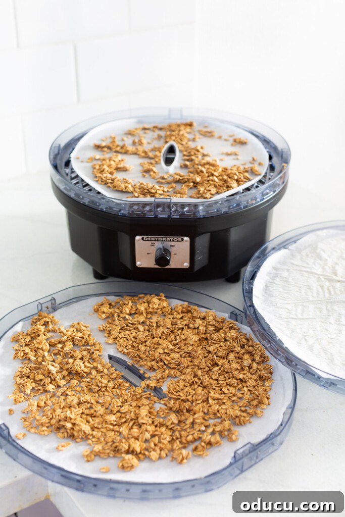A dehydrator open showing trays with crunchy rawnola being dried.