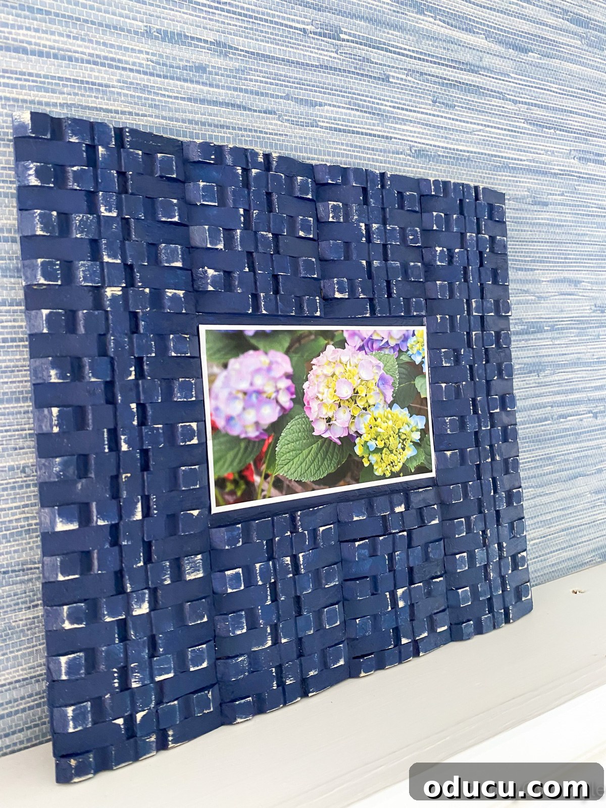 DIY picture frame with clothespins leaning against a wall on a ledge.