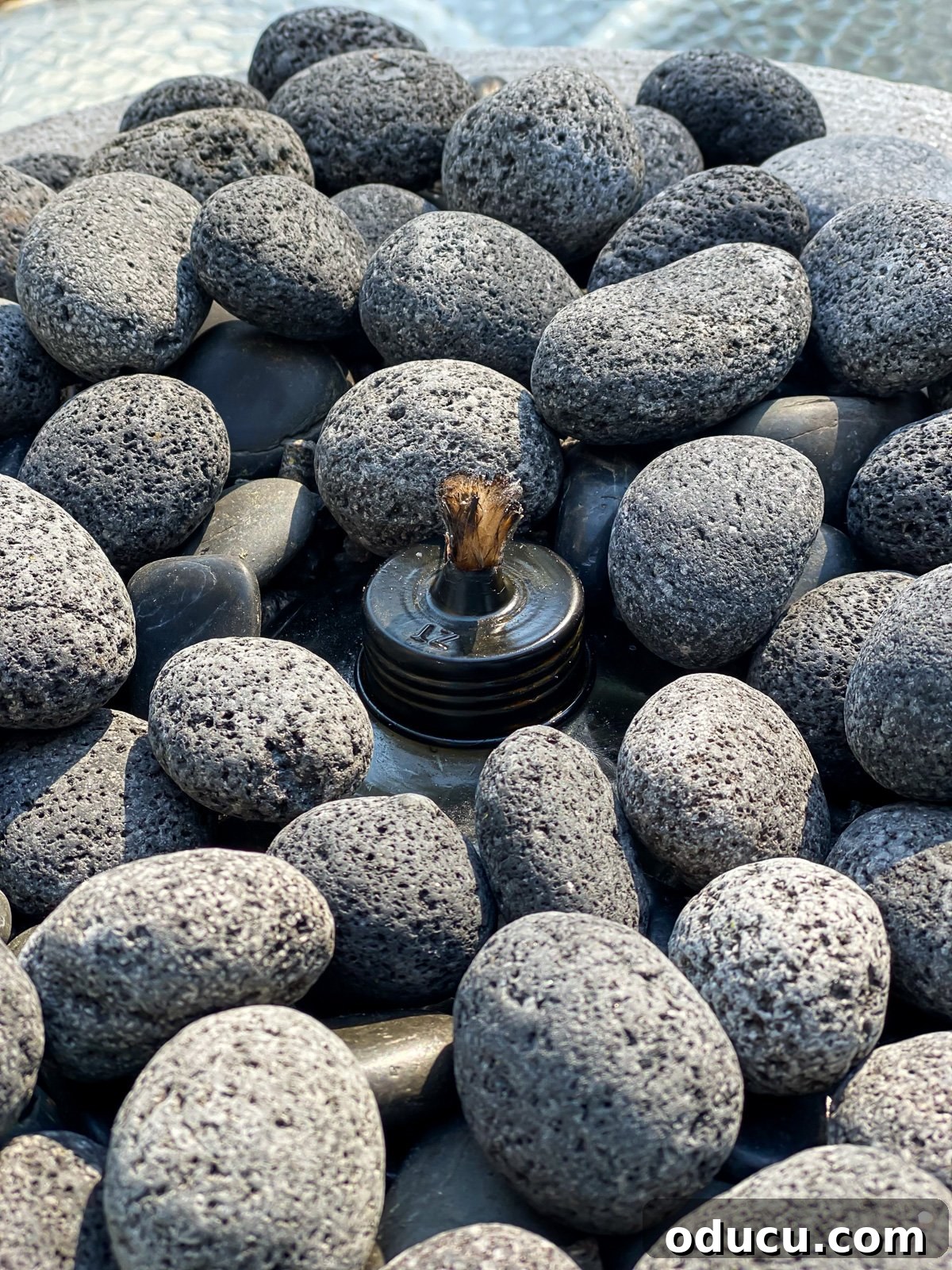 Close up of covered tabletop torch in planter filled with stones.