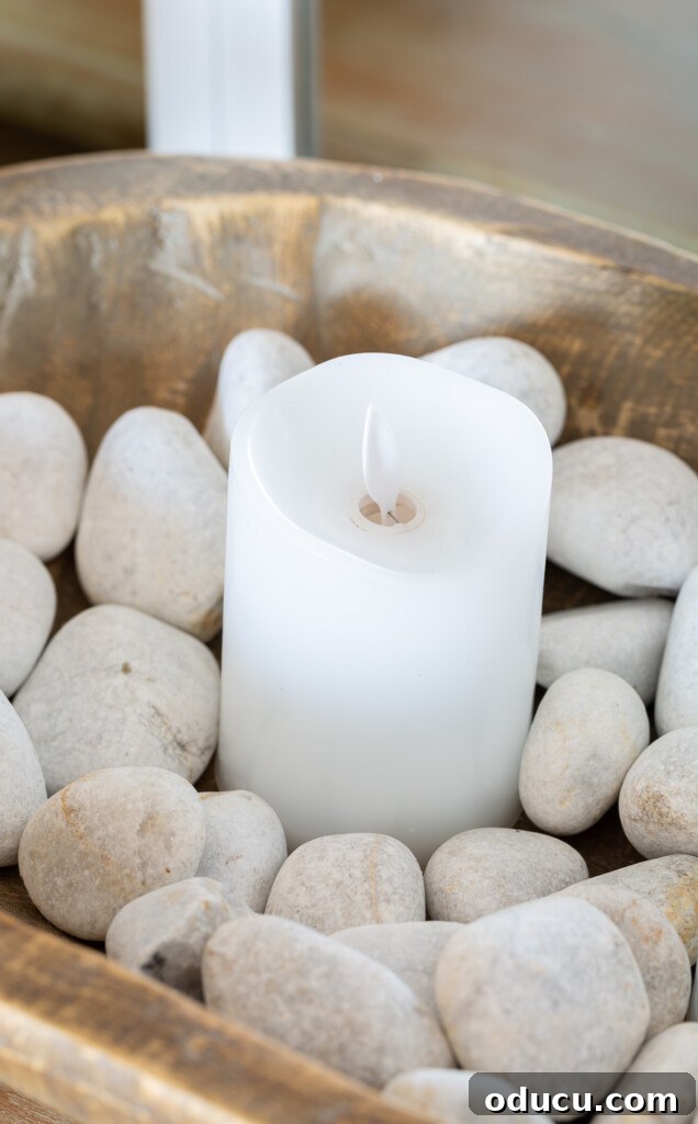 12 Affordable DIY Summer Decor Projects 19 A close-up shot of a single candle nestled within a dough bowl filled with decorative rocks, used to adorn a living room for summer.