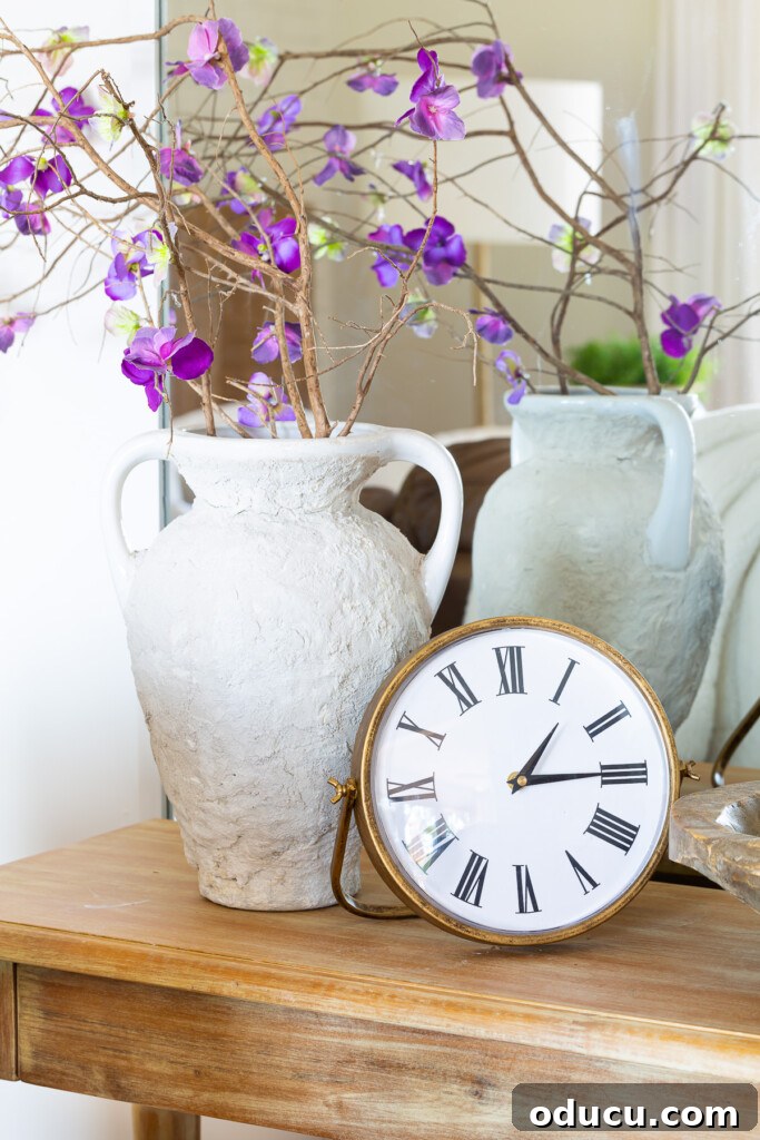 12 Affordable DIY Summer Decor Projects 22 An elegant console table in a living room, adorned with faux flowers and a prominent table clock, suggesting unique ways to style a home any season.