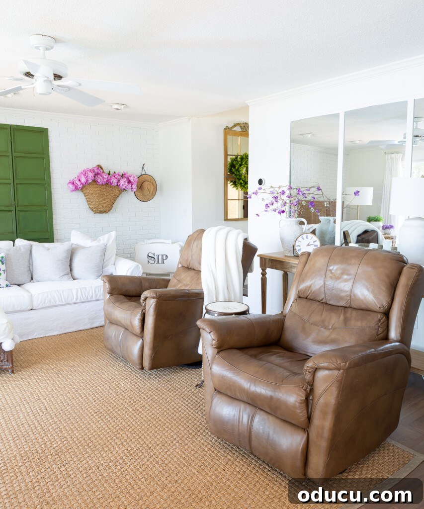 12 Affordable DIY Summer Decor Projects 9 A newly rearranged living room for summer, featuring two identical recliners and a pristine white sofa, accented with soft pink and green hues.