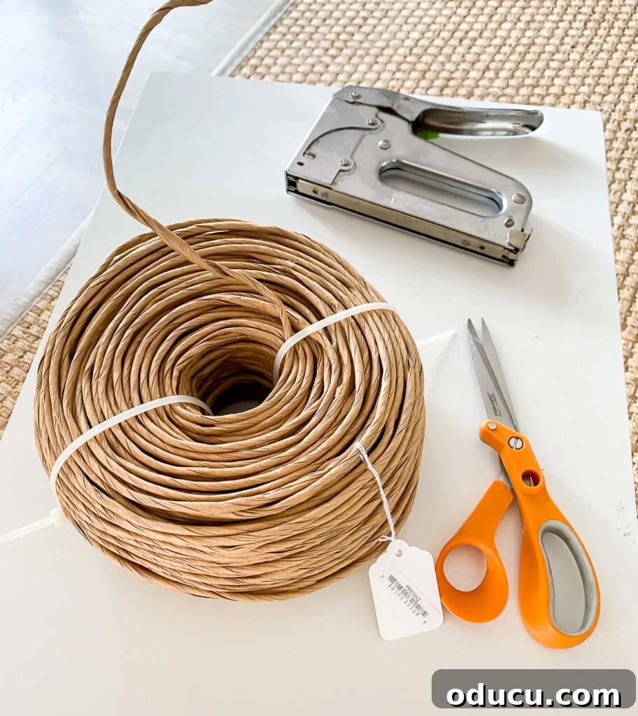 Designer Dupe Two-Tier End Table Makeover 14 A curated collection of supplies necessary for a wood end table makeover, including paint, brushes, fiber rush, and tools.