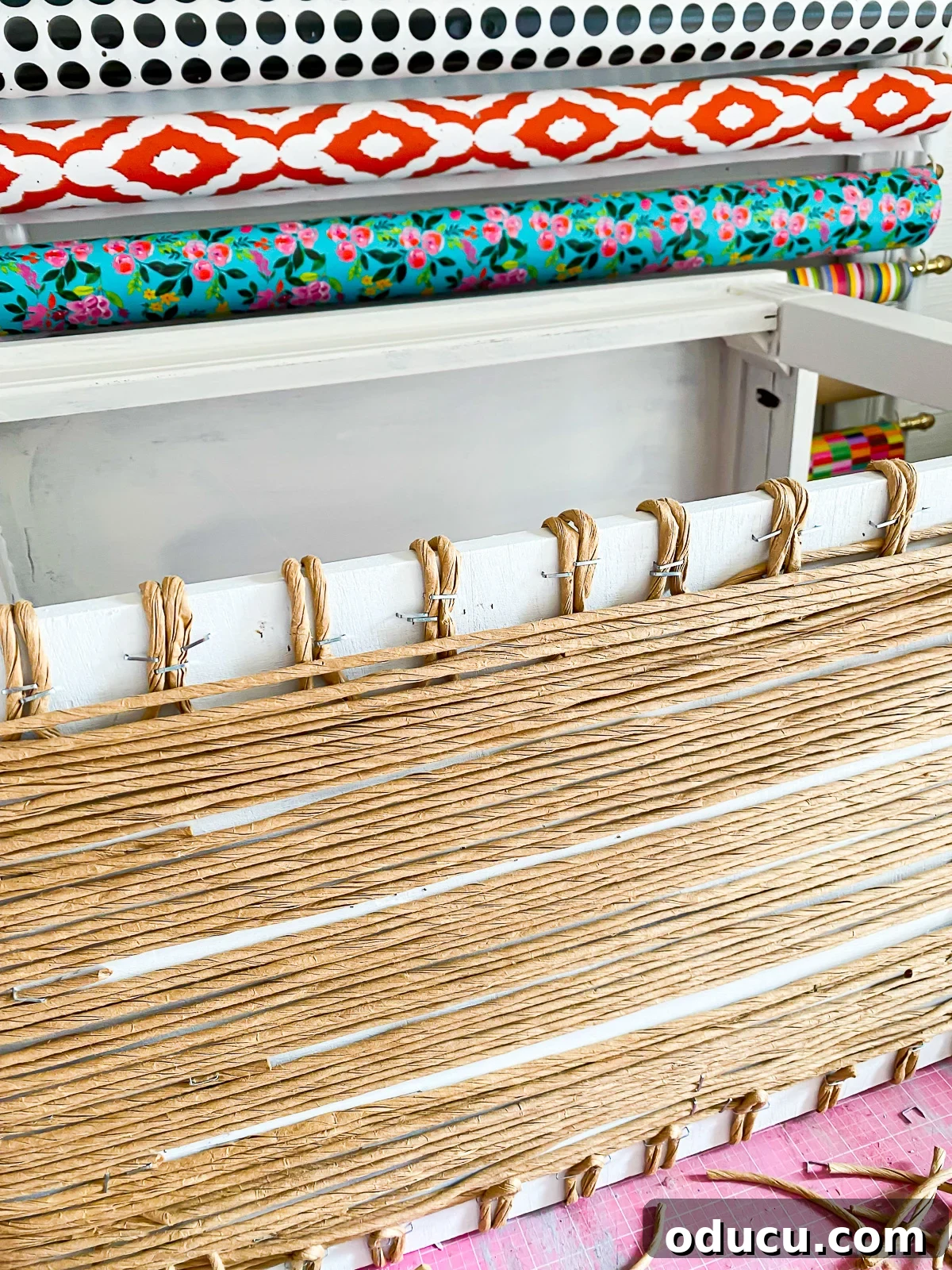 Designer Dupe Two-Tier End Table Makeover 25 Instructions on how to securely fasten loose ends of fiber rush under the shelf of a side table during a makeover, using a stapler.