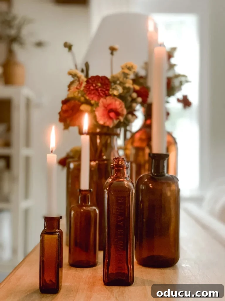 Fashion Forecast 2 A beautiful collection of amber bottles, some holding flickering candles and others adorned with delicate flowers, creating a warm and inviting fall decor display.