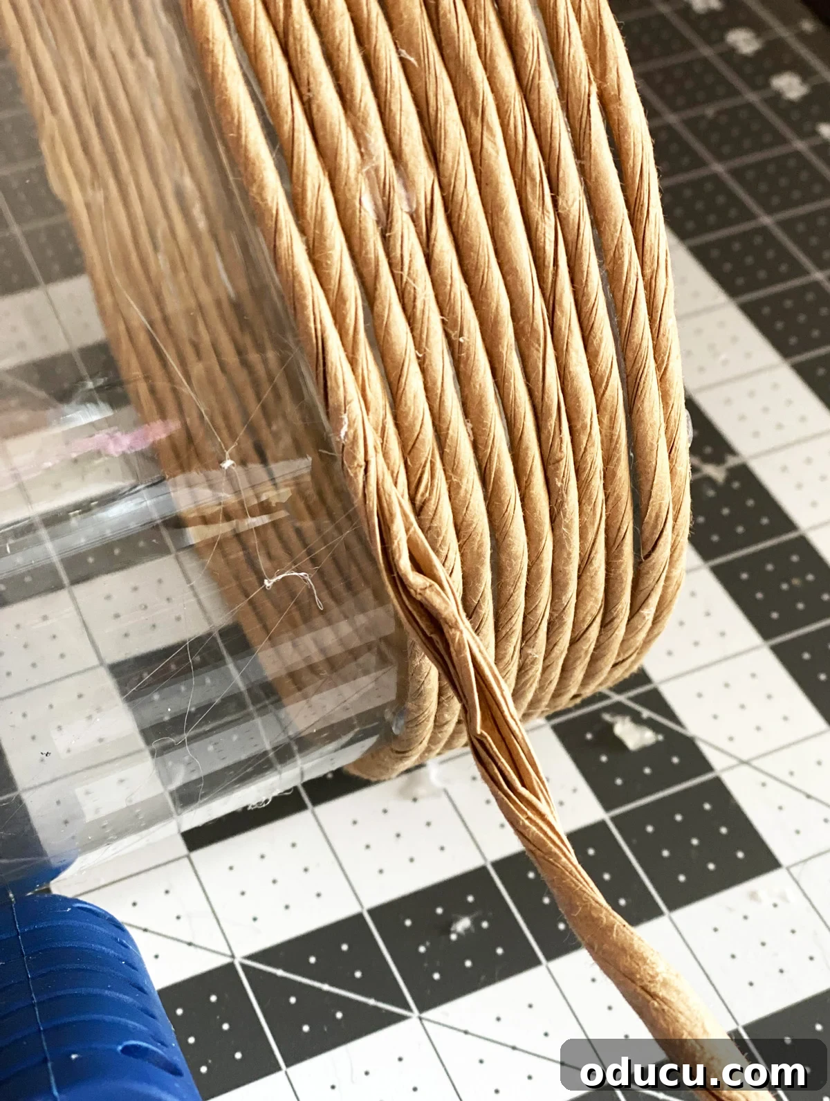 paper cord being wrapping and glued onto a glass vase on worktable
