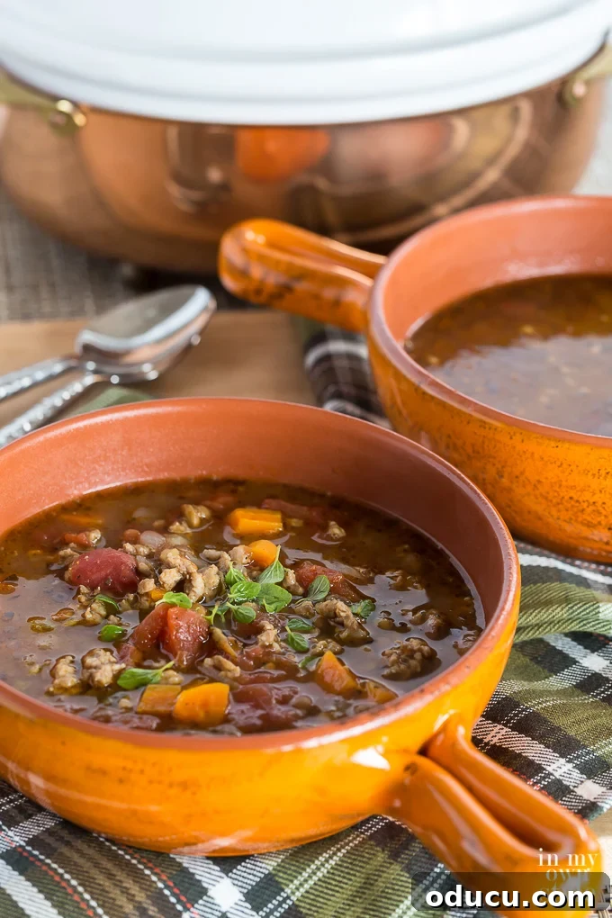 A vibrant orange bowl filled with a rich and hearty Sausage and Lentil Soup, a perfect comforting meal for autumn.
