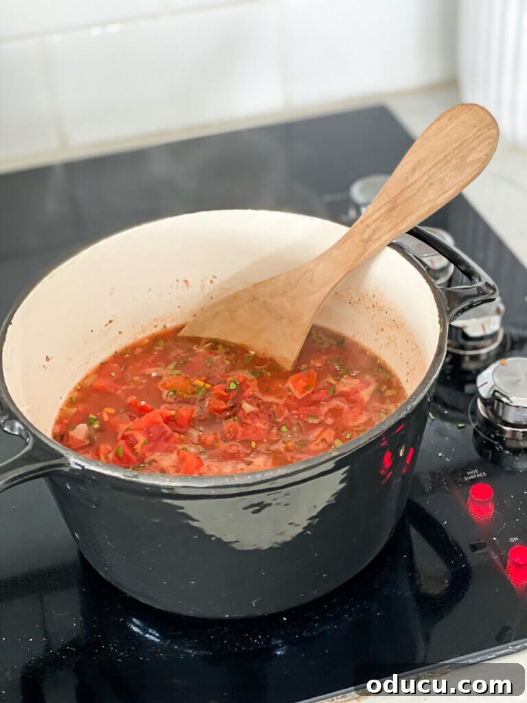 A pot of fire-roasted vegan tomato soup gently simmering on a stove, filling the kitchen with inviting aromas.