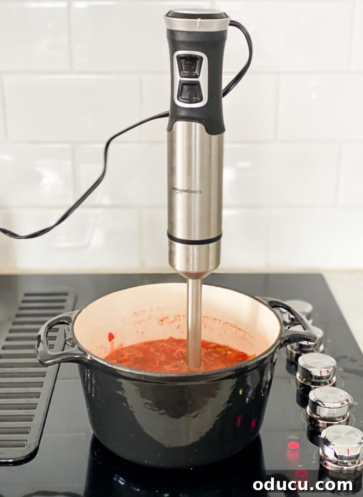 Cozy Autumn Bean and Greens Soup 5 an immersion blender submerged in a pot of cooking soup on a stove