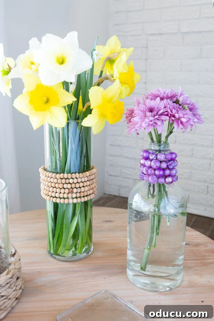 Repurpose Your Jewelry for Home Decor 3 A glass vase and a glass bottle beautifully adorned with colorful old jewelry necklaces, creating cheerful spring decor.