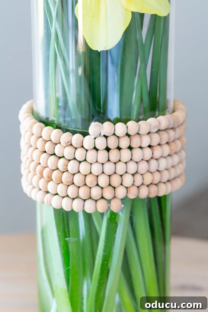 Repurpose Your Jewelry for Home Decor 4 A glass vase adorned with repurposed wood beads, offering a natural and colorful spring decor element.