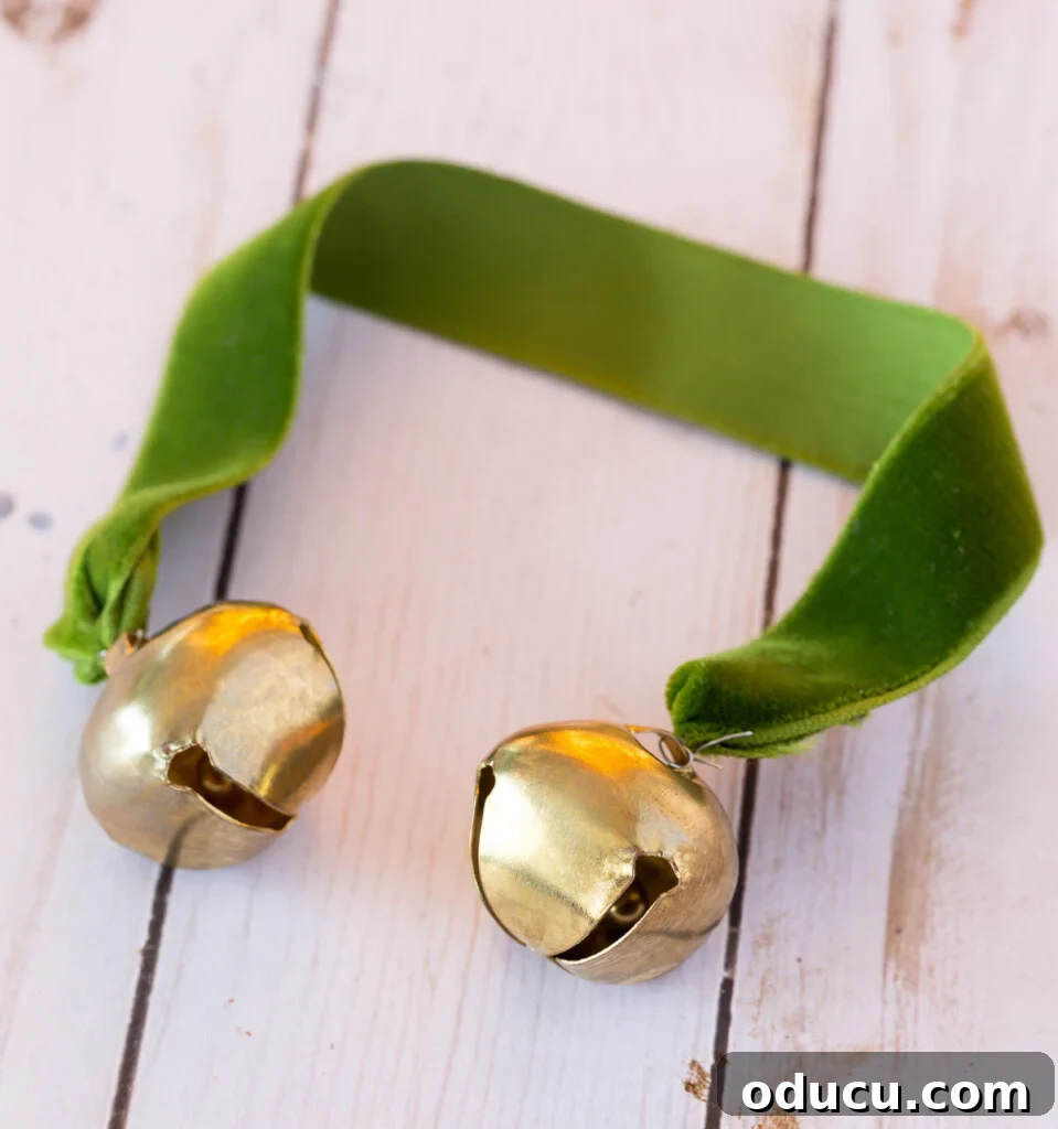2 gold jingle bells wired to the ends of a piece of green velvet ribbon.