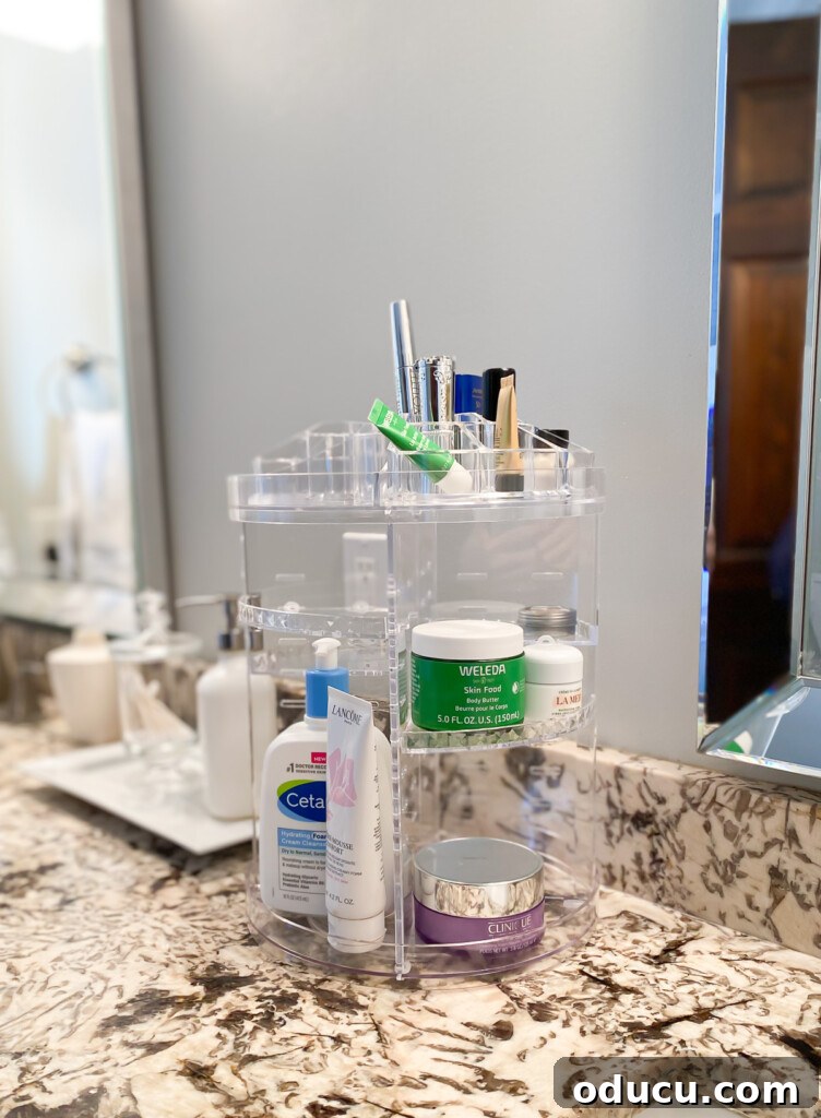 Triple-Tier Revolving Bathroom Organizer 3 A clear acrylic 3-tier rotating bathroom skincare organizer on a counter.