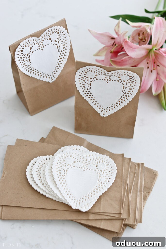 Style Digest 129 2 Two delicate white heart doilies gracefully adorning rustic brown paper lunch bags, evoking a cozy and charming Valentine's Day theme, perfect for small gifts or decor.