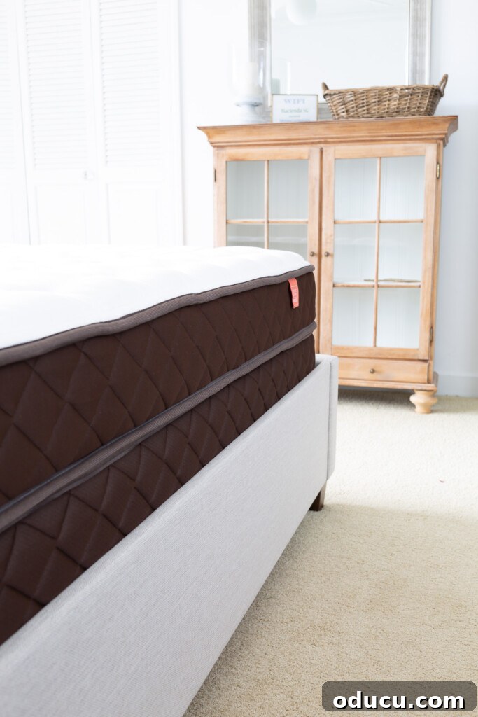 Christeli Charleston Mattress: What You Need to Know 12 side view of a Christeli Charleston 14.5 mattress and base in an Eastman upholstered platform bed in a bedroom.