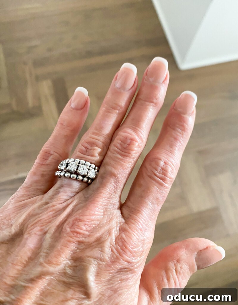 The Friday Connection 10 A hand adorned with elegantly manicured nails and delicate beaded silver rings.