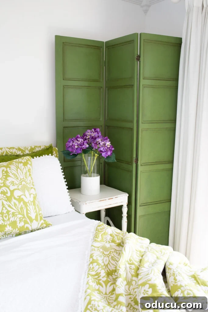 Revitalize Your Bedroom: Creative Decor Transformations 7 A beautifully glazed green painted decorative screen stands prominently in a green and white guest room, serving as a vibrant focal point and adding artistic flair.