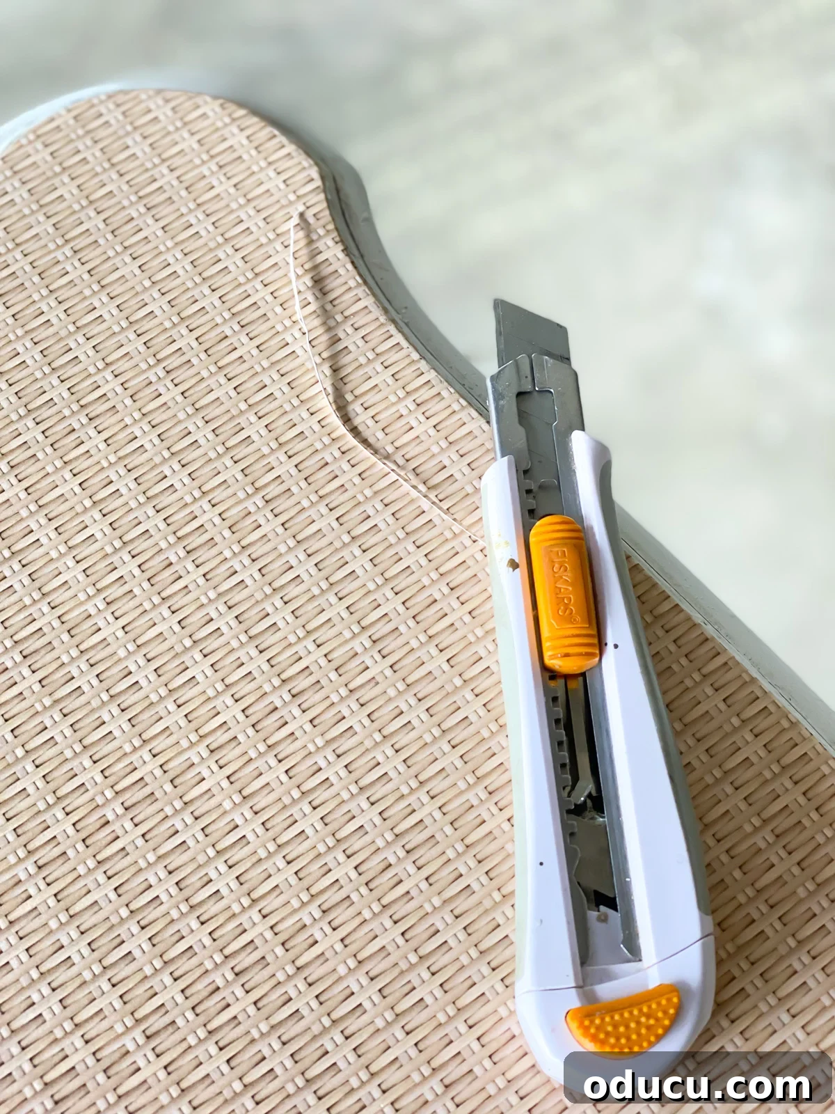 craft knife trimming the edge of wallpaper on furniture.