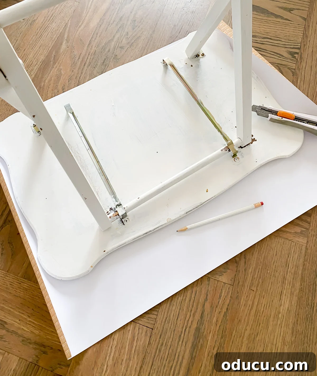 tray table placed upside down on wicker print paper so a tracing of the top can be made to perfectly fit the top shape.