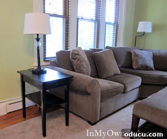 After shot of living room makeover showing black stained table next to a light brown sofa.